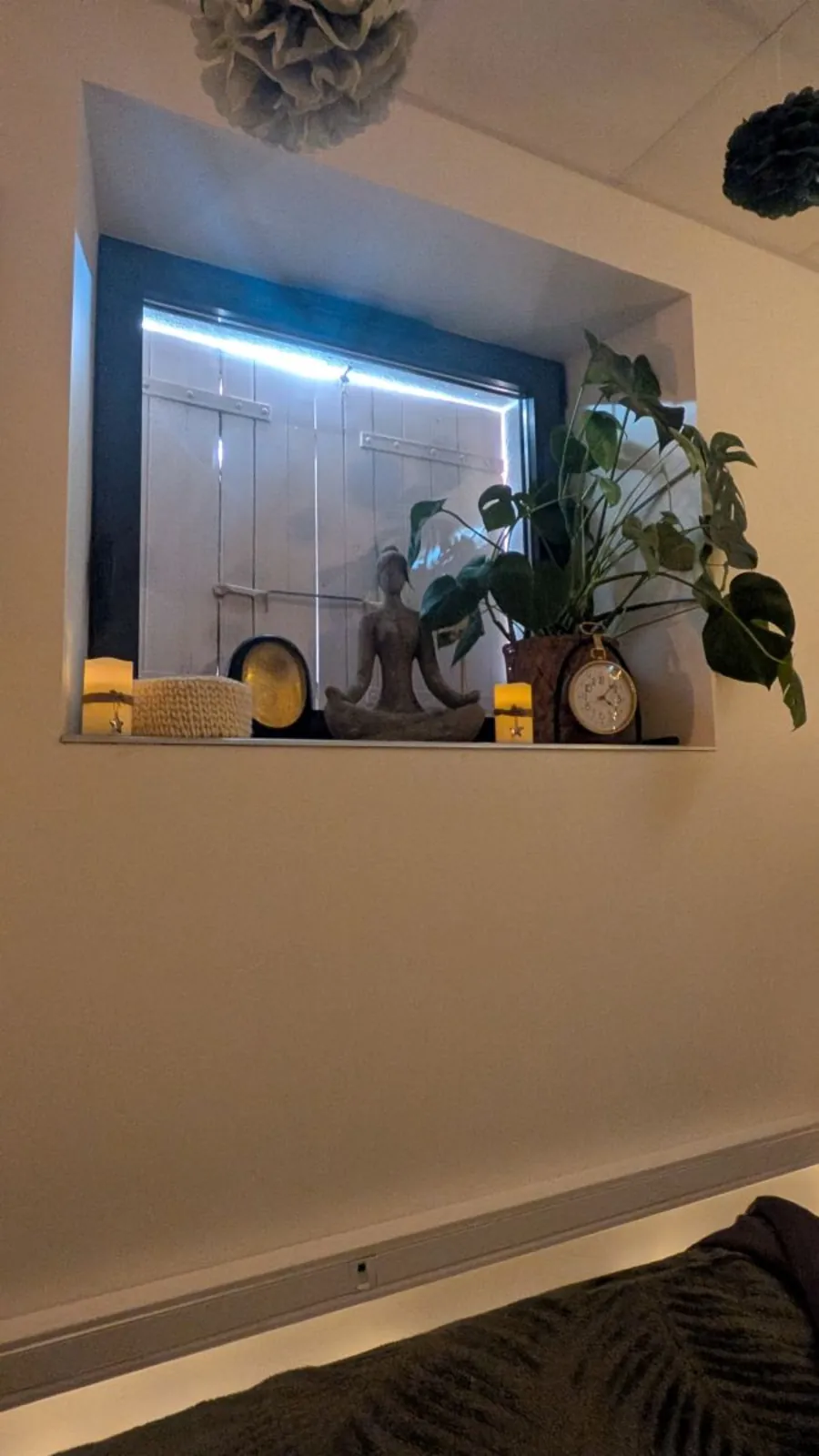 Niche décorative avec statuette zen, bougies et plante verte