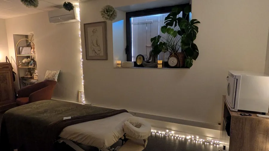 Table de massage prête à accueillir, ambiance tamisée et guirlandes lumineuses